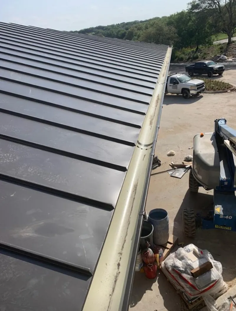 Standing seam panel and gutter detail on a metal roofing jobsite in Troy